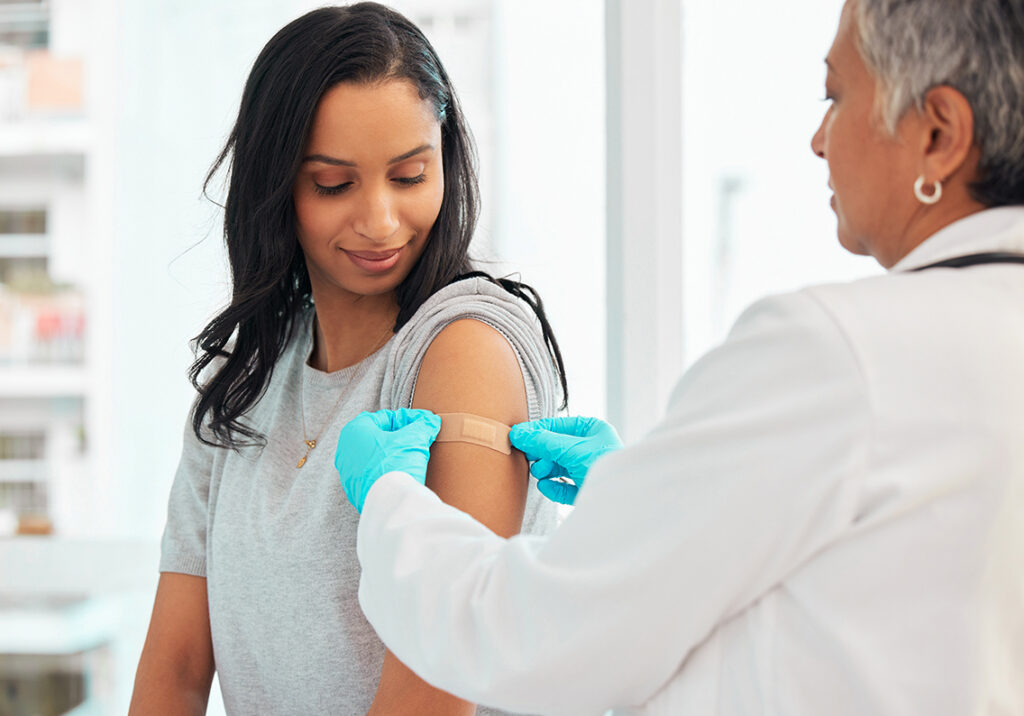 Healthcare, woman and doctor with plaster, vaccination and consultation in a hospital, cure and disease. Female patient, client and medical professional with care, vaccine and injection for safety.